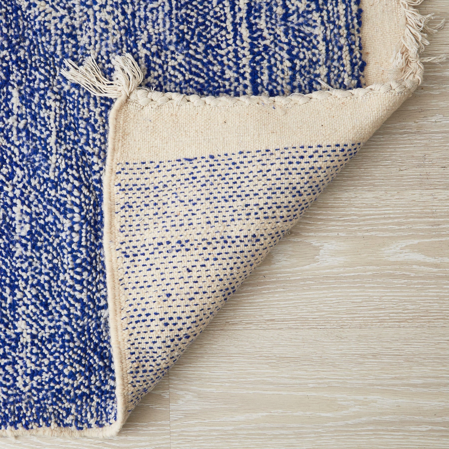 tappeto beni ourain a tinta unita con colore blu melange e frange bianche dettaglio del retro