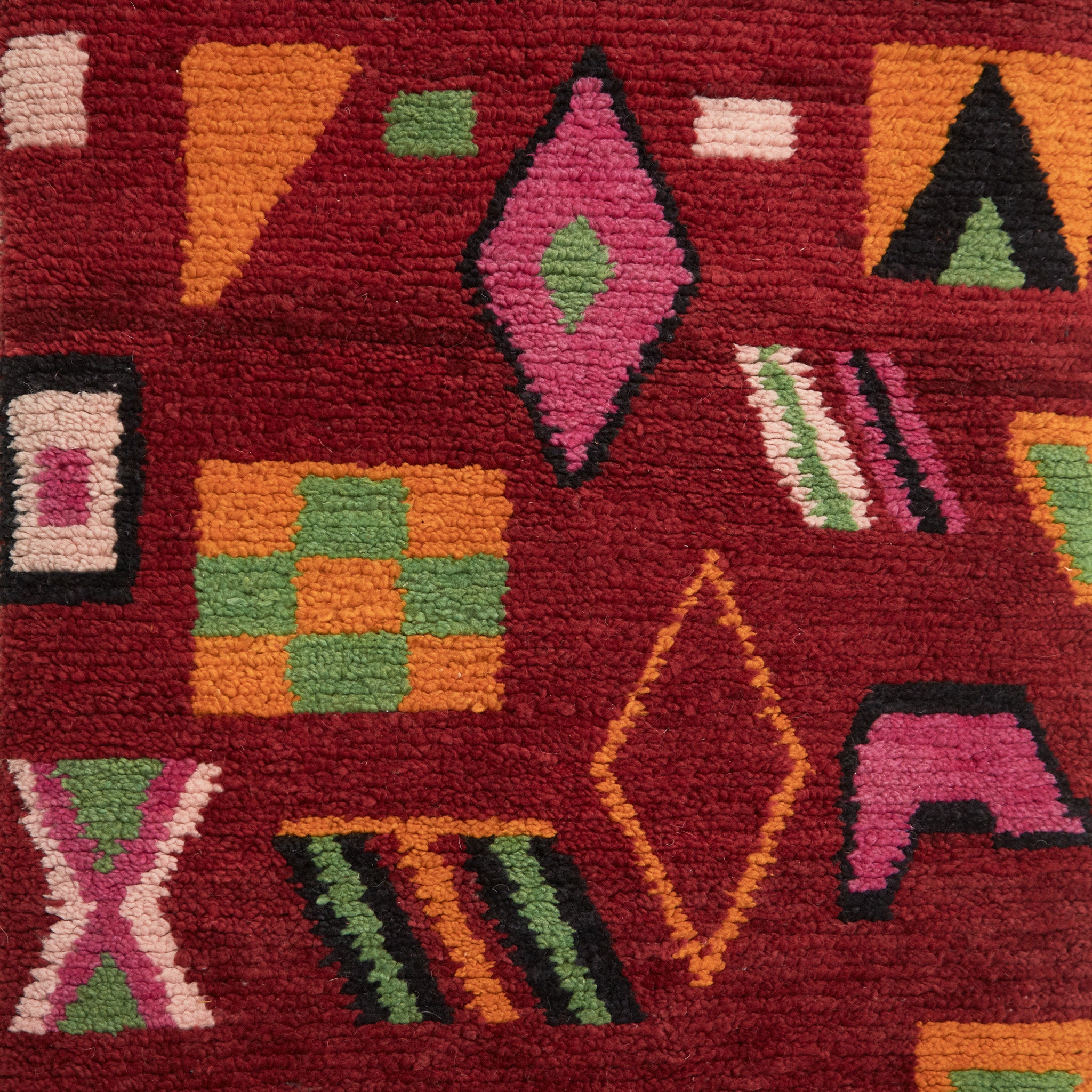 dettaglio dei simboli tradizionali che ricordano delle figure geometriche di un tappeto su base rossa