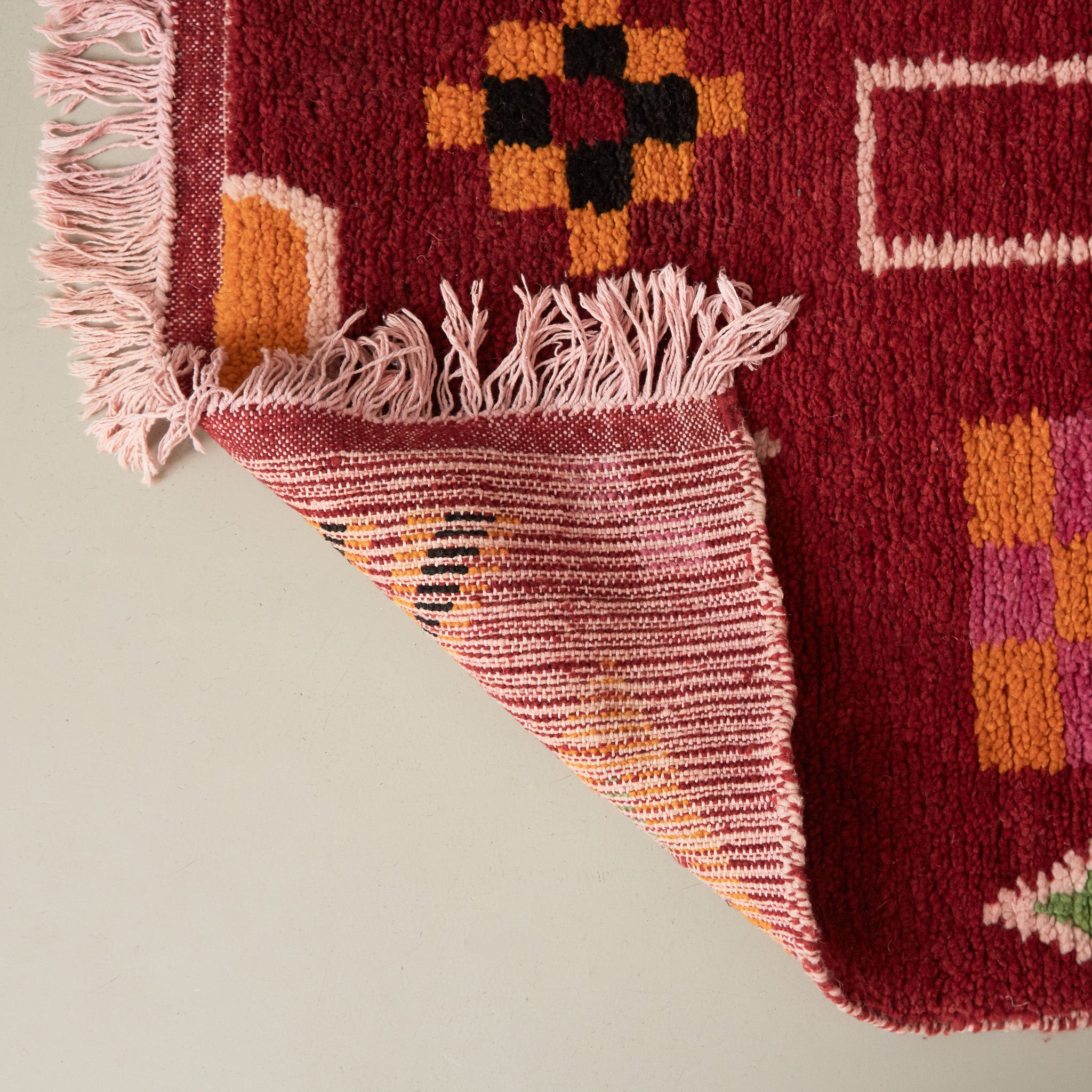 dettaglio della lavorazione di un tappeto boujaad annodato con lana colorata di rosso