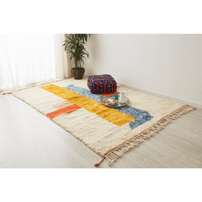 tappeto contemporaneo grande con 3 forme geometriche di diversi colori su base bianca e doppia frangia disteso sul pavimento