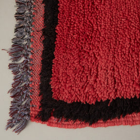 dettaglio dell'angolo e della frangia di un tappeto azilal vintage per corridoio in lana rossa con bordo nero