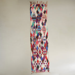 tappeto passatoia boucherouite vintage realizzato con stracci di tessuti per creare dei rombi colorati e alcuni inserti in lana disteso