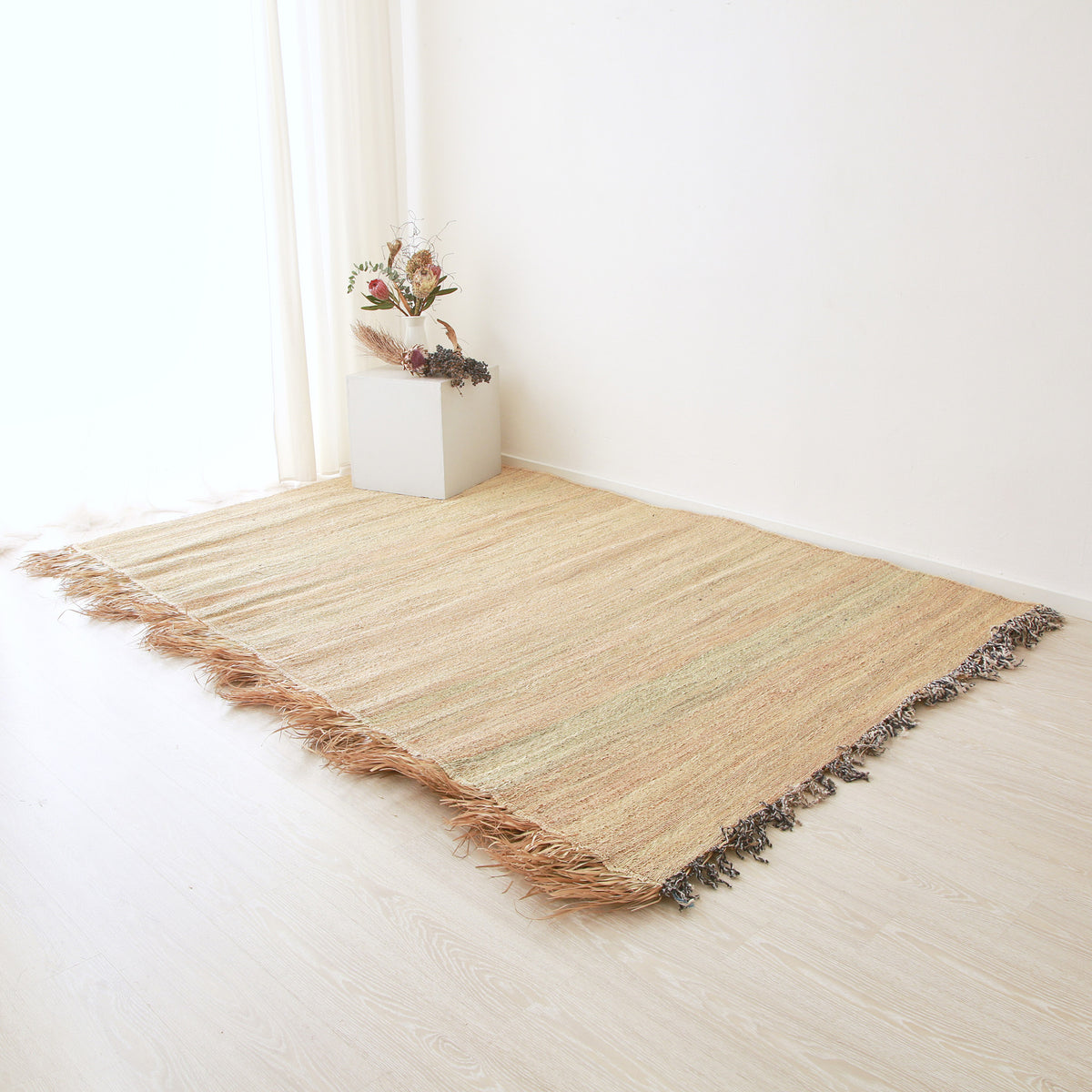 tappeto stuoia hassira senza ricami intrecciata con paglia di palma con un frangia laterale in paglia su pavimento con una composizione floreale