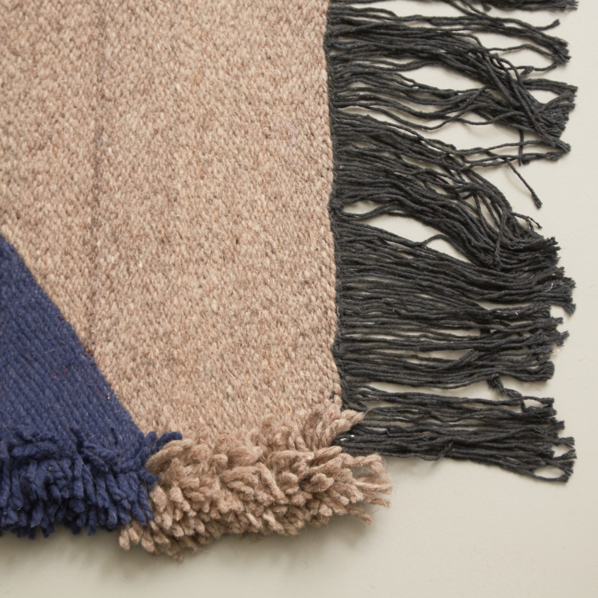 dettaglio di due frange e della lana intrecciata di un piccolo tappeto taznakht a tessitura piatta con lana colorata blu grigio beige 